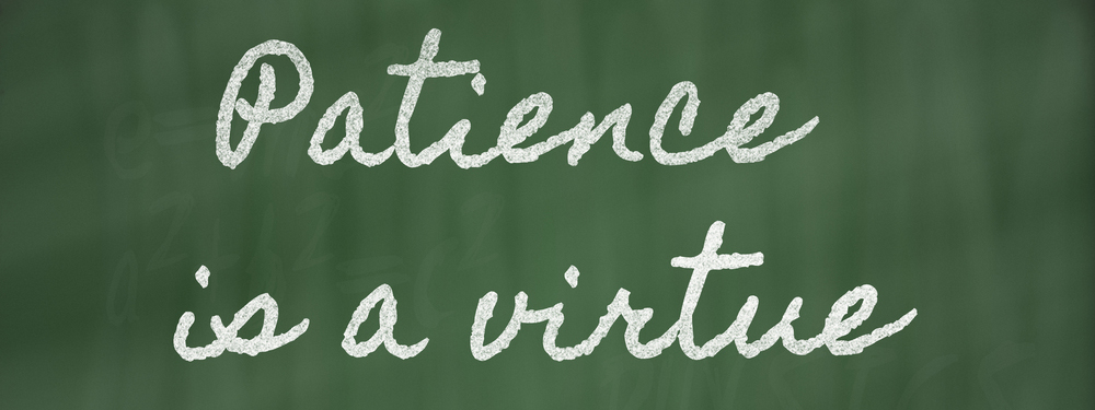 Handwriting on a blackboard reading: Patience is a virtue